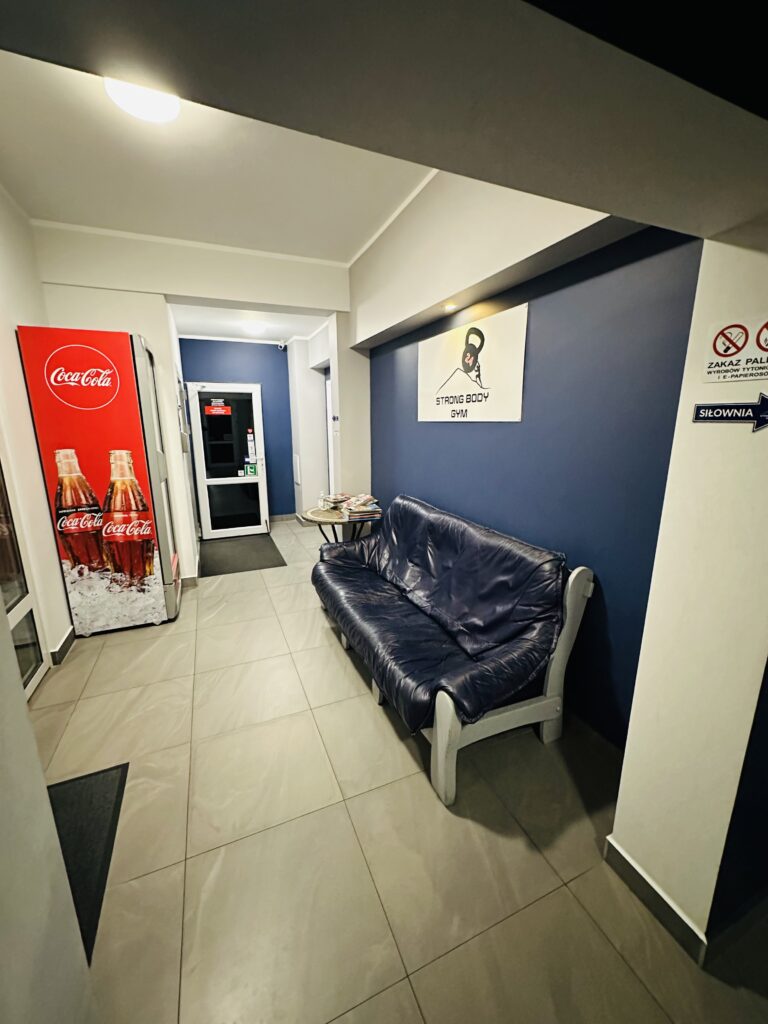 Na zdjęciu wnętrze poczekalni w siłowni strongbodygym, gdzie można odpocząć na kanapie.