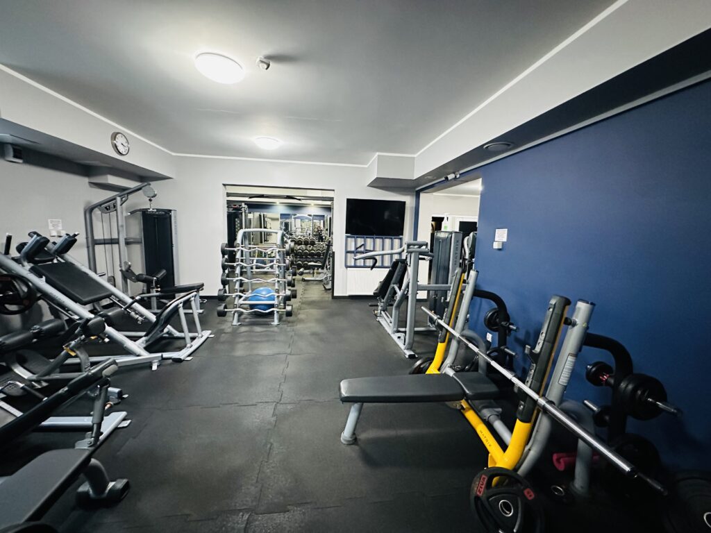 Na zdjęciu ukazane jest wyposażenie w sprzęt sali do ćwiczeń w siłowni.