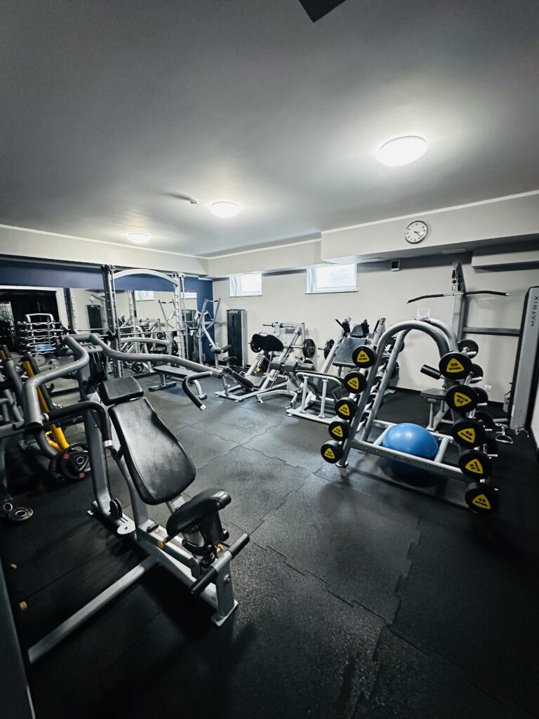 Na zdjęciu przedstawione jest wnętrze sali ćwiczeń razem ze sprzętem do ćwiczenia.