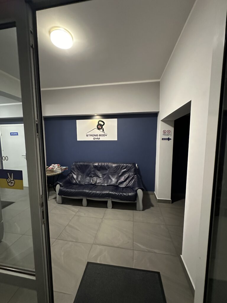 Na zdjęciu pokazane jest wnętrze siłowni z miejscem na odpoczynek - kanapą.